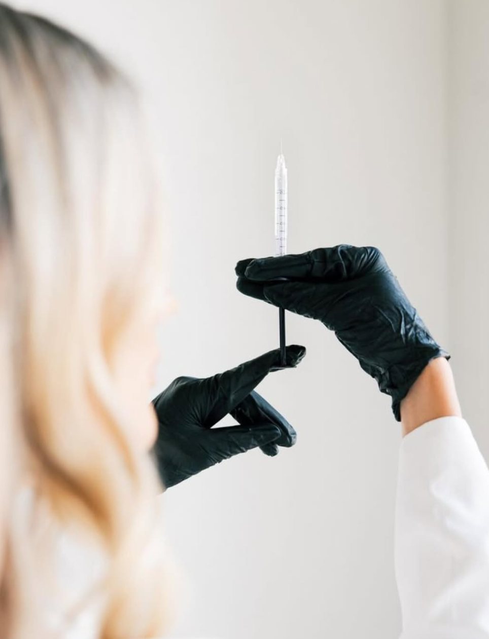 Close-up of gloved hands holding a treatment syringe